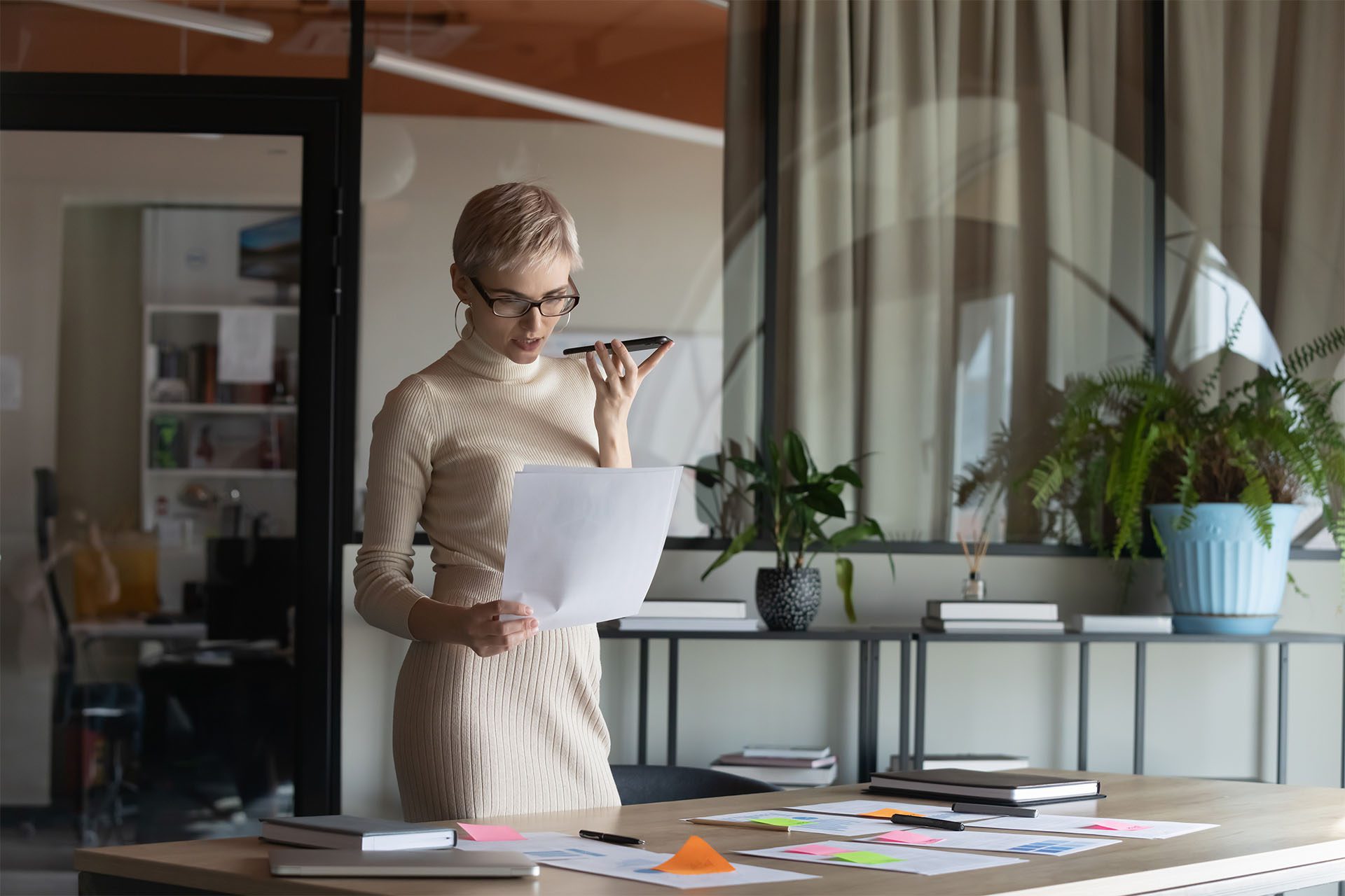 Woman in dress in office using phone for voice search