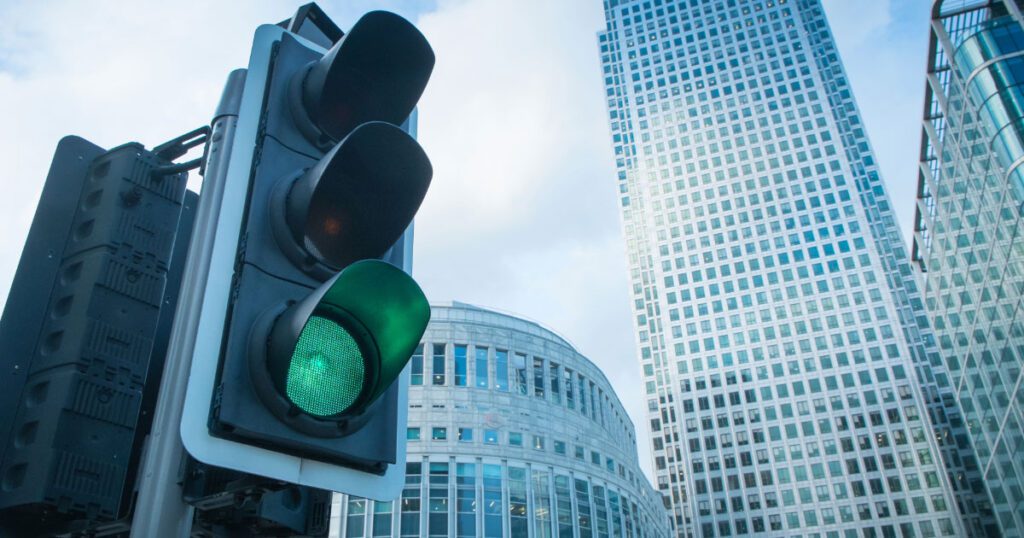 A green traffic light with a skyline in the background.