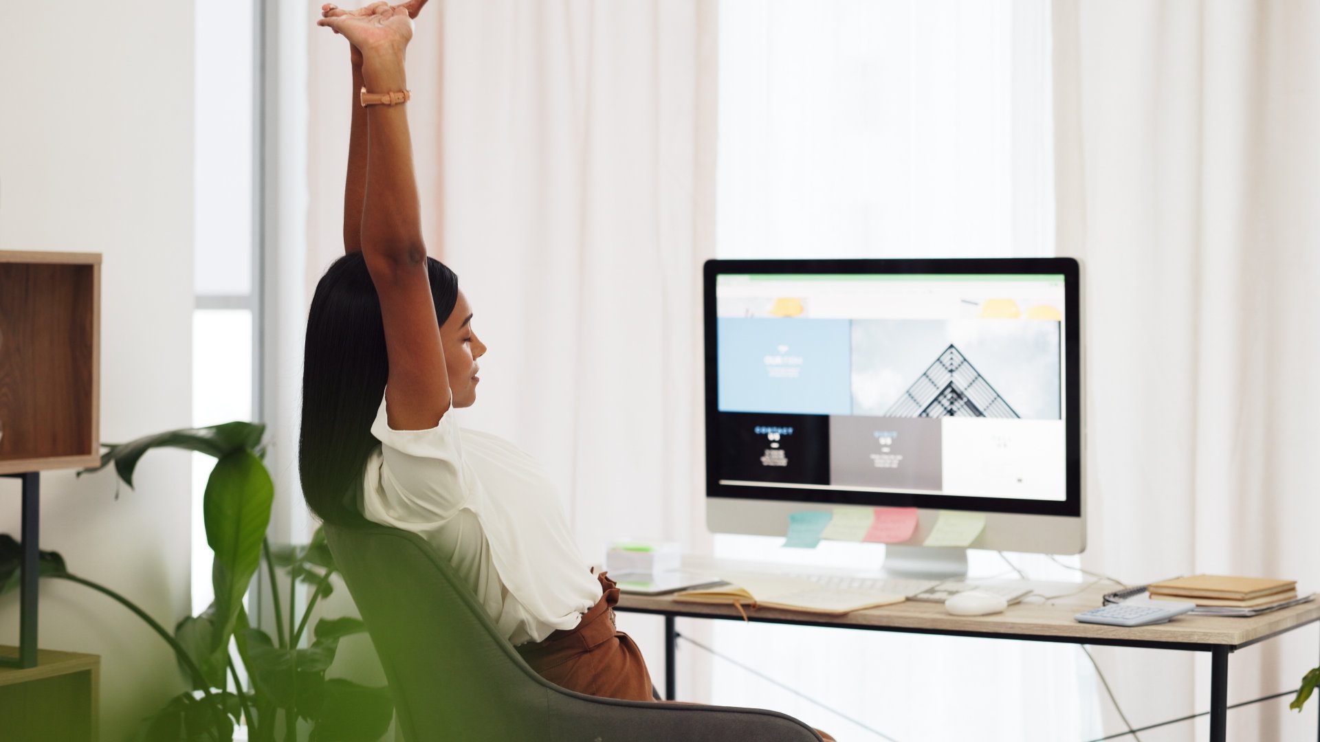 Women working on a WordPress website sitting on a chair at her desk stretching.
